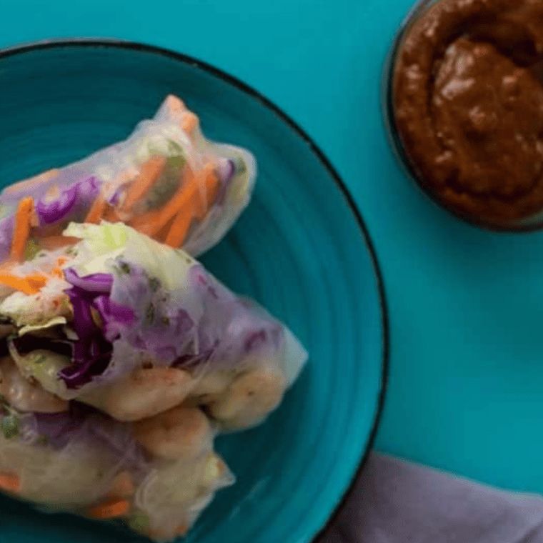 Golden crispy air fryer rice paper rolls filled with prawns and fresh vegetables, served with peanut dipping sauce.