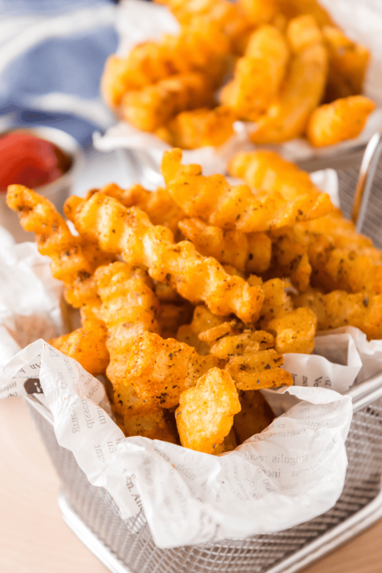 Close-up of golden crinkle cut fries inspired by Shake Shack, crispy and ridged in a basket ready for dipping.