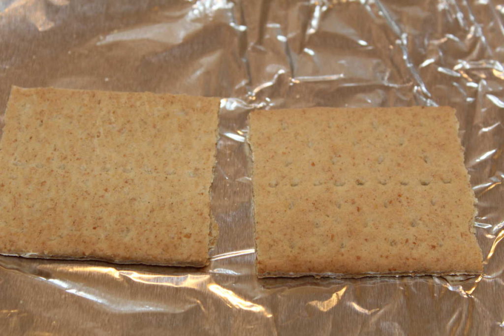 two graham cracker halves on a sheet of foil