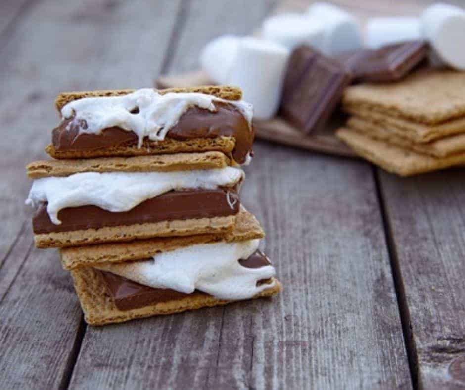 gooey air fryer s'mores on a wooden deck with ingredients in background