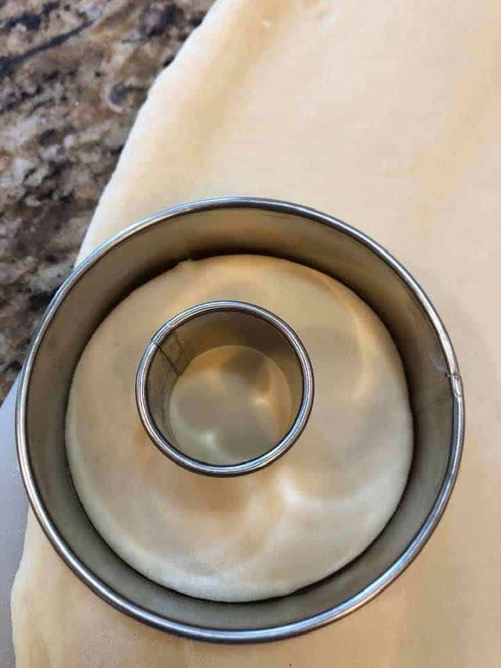 small round biscuit cutter inside a larger cutter on rolled out dough
