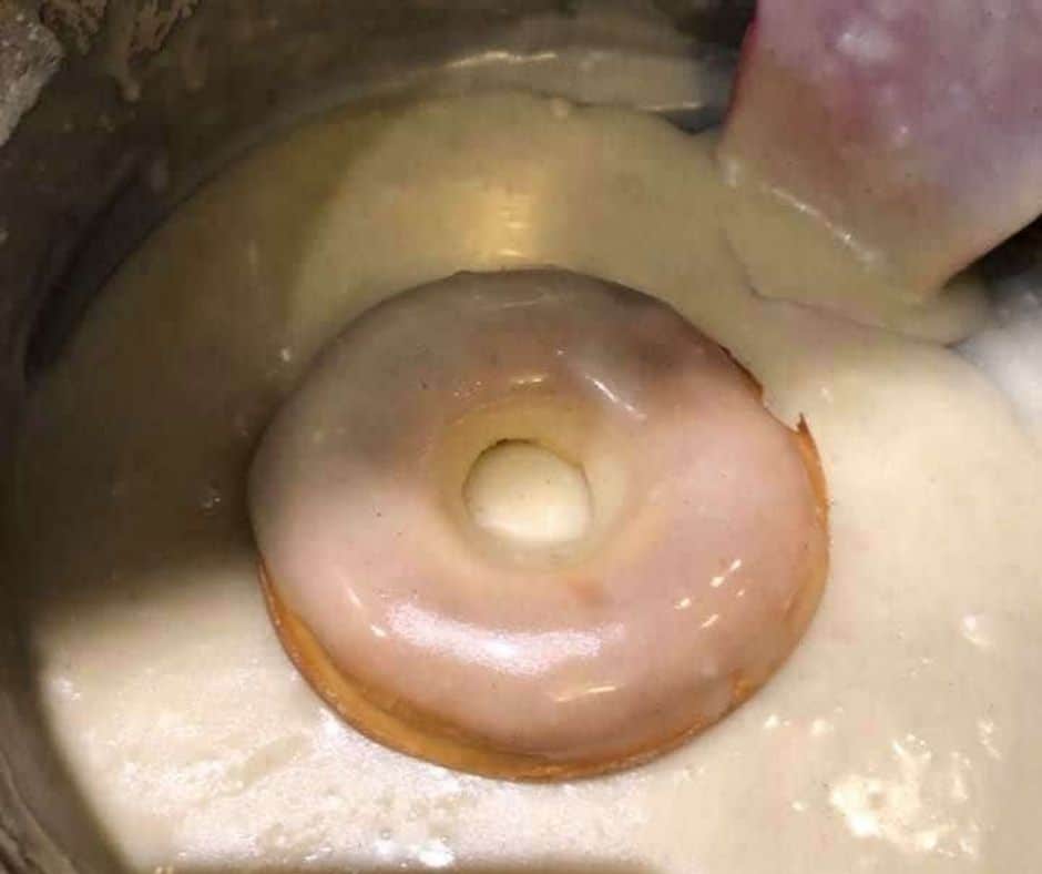 cooked donut in a bowl of white glaze
