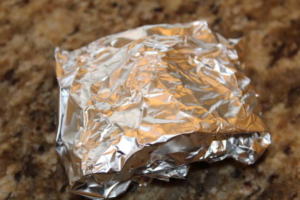 air fryer smores wrapped in tin foil on a marble counter