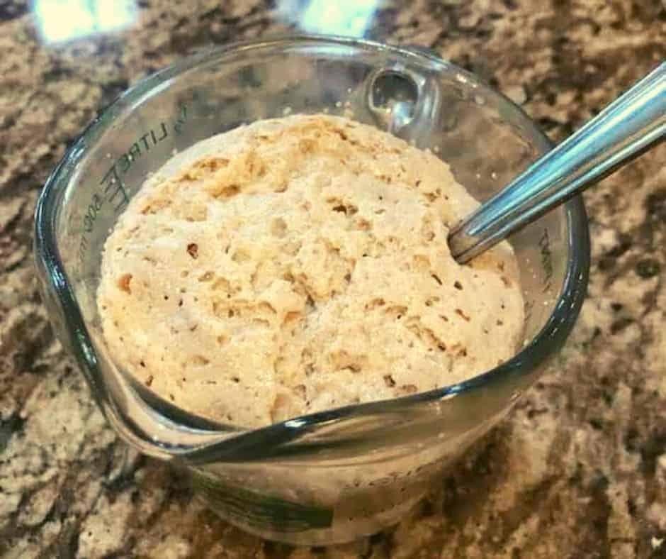 yeast proofing in a glass measuring cup with a spoon
