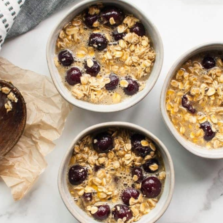 Cherry oatmeal in oven-safe ramekins on a white flat surface