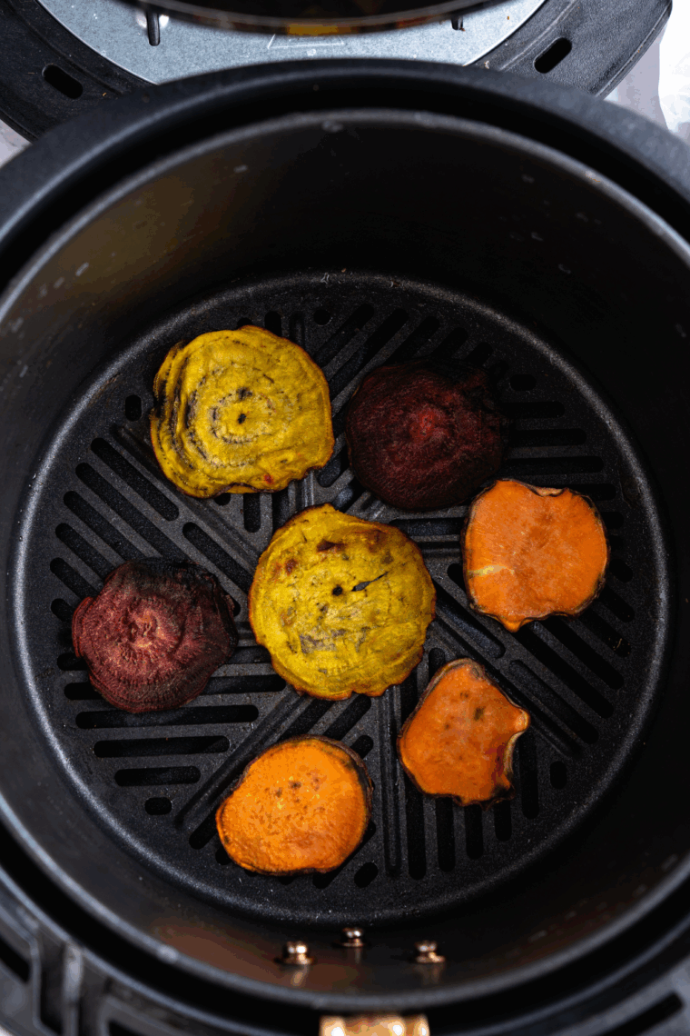 Homemade air fryer Terra-style vegetable chips made with colorful root vegetables like beets, sweet potatoes, and purple potatoes on a white plate.
