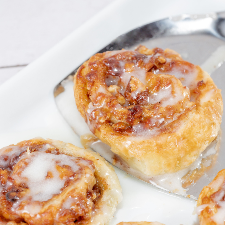 Cooked Air Fryer Puff Pastry Cinnamon Rolls served on white plates with a light glaze.