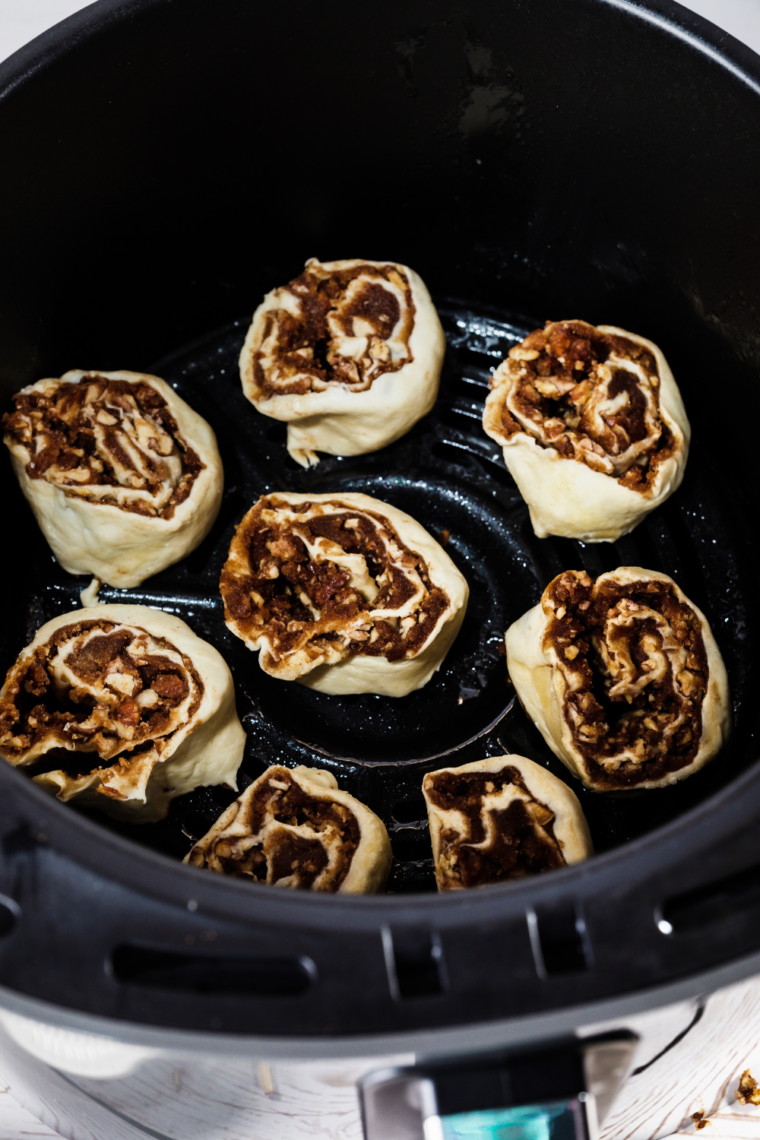 Placing cinnamon rolls in the air fryer for cooking.