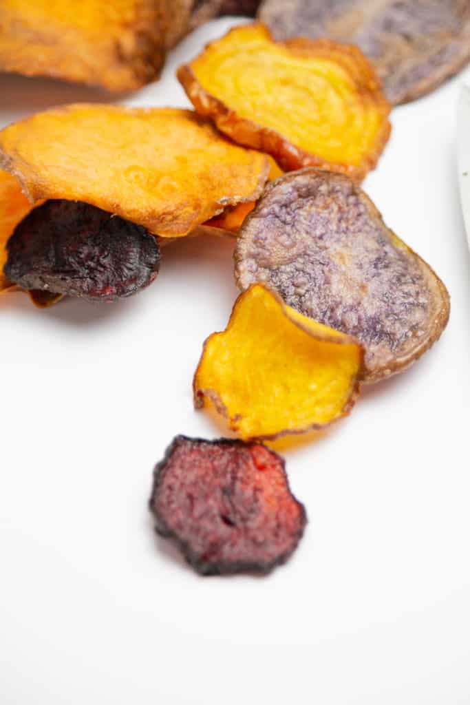 closeup: homemade veggie chips from air fryer scattered on a white counter