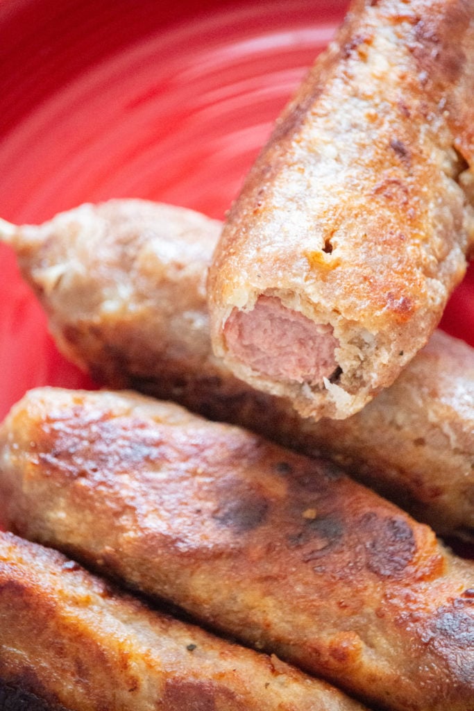 Golden keto corn dogs cooked in the air fryer, served hot on a plate with wooden skewers.