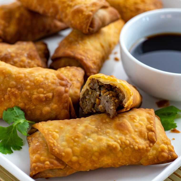 closeup: a plate full of several lumpia with one with a bite taken out of it