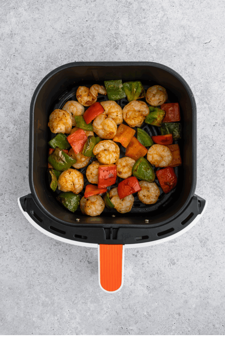Cooked shrimp and vegetables in the air fryer basket.