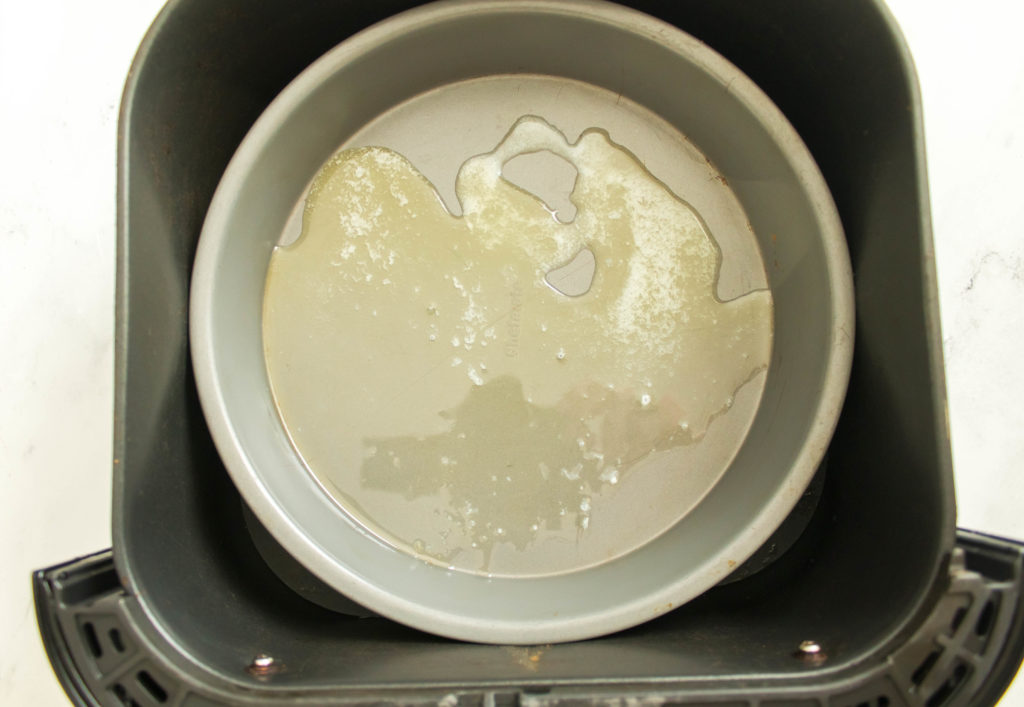 round metal pan with oil in air fryer basket