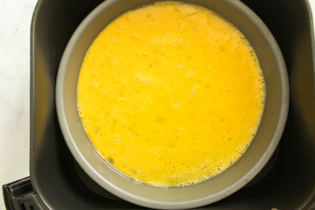 whisked eggs in a metal pan inside air fryer