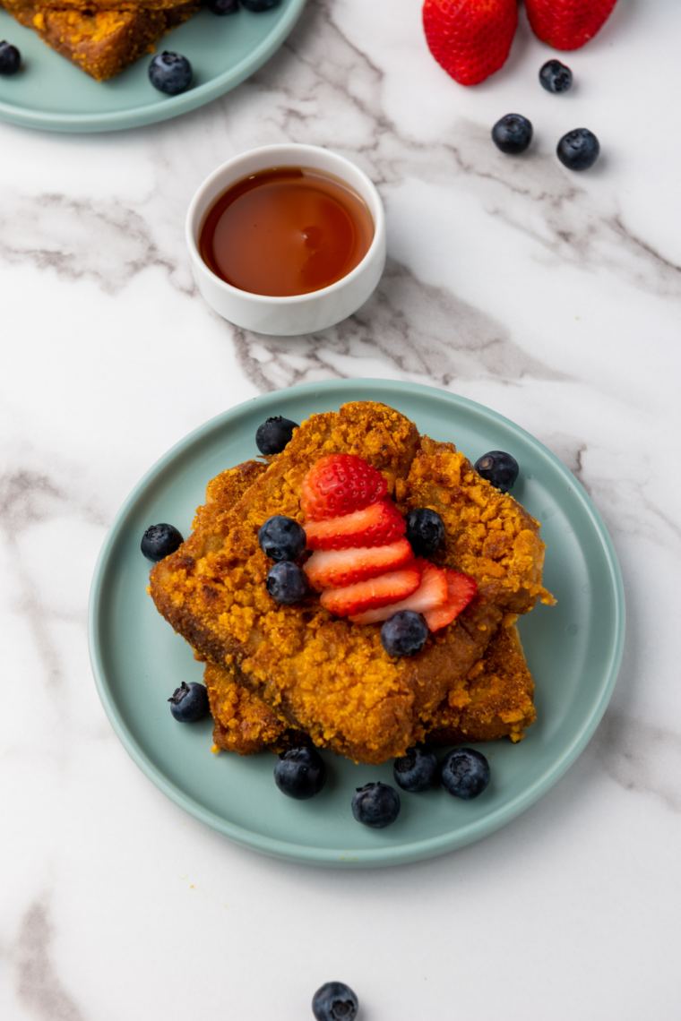 Air fryer Captain Crunch French toast slices, golden and crispy, served on a plate with syrup and fresh fruit