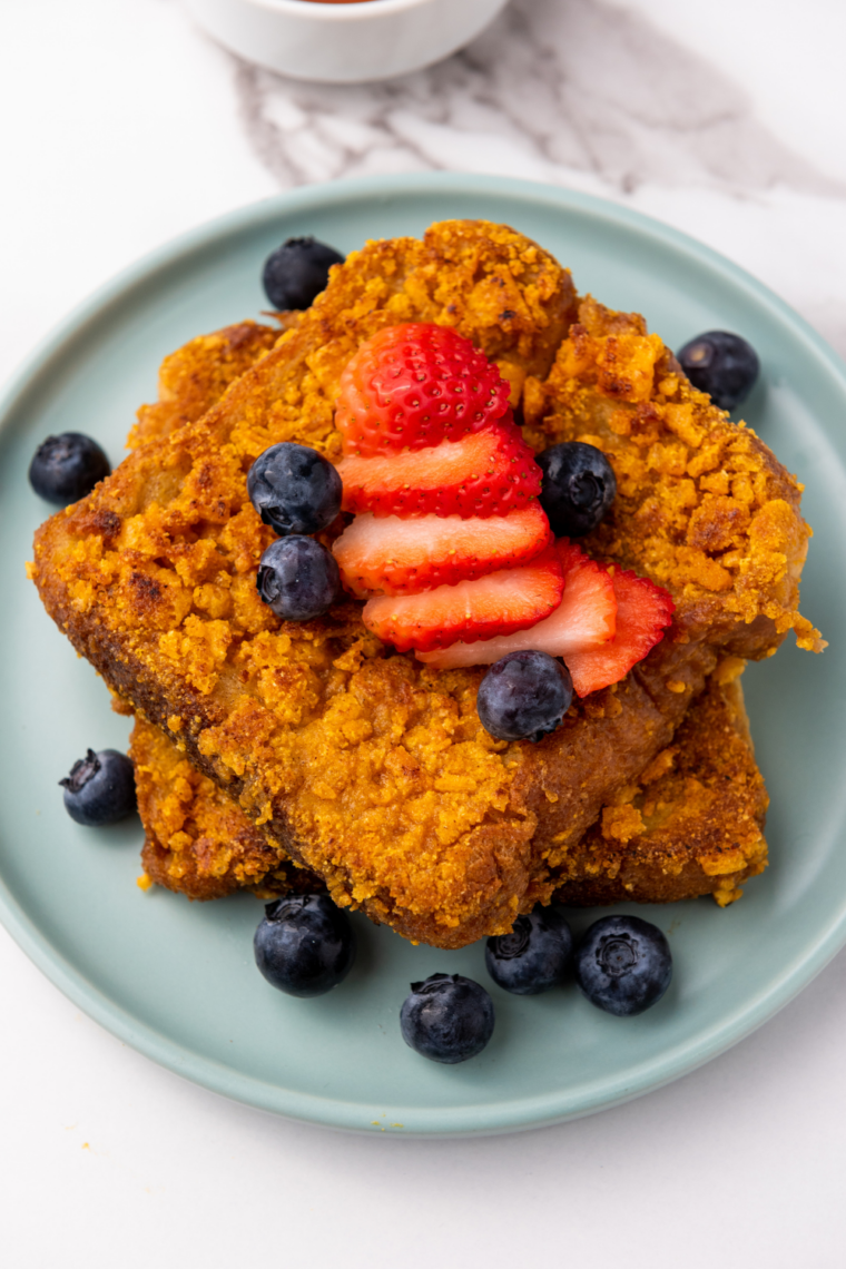 Air fryer Captain Crunch French toast slices, golden and crispy, served on a plate with syrup and fresh fruit