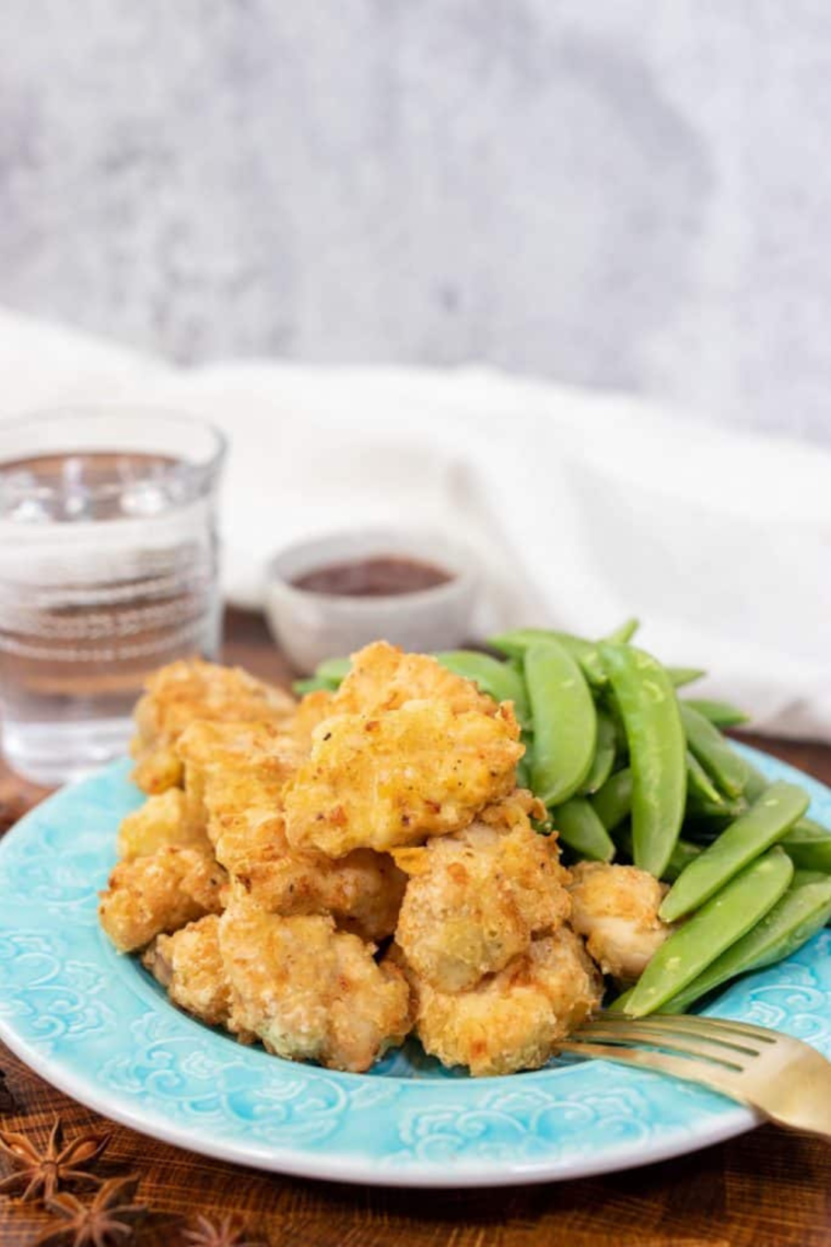 Plate of Chinese chicken fingers on a plate with dipping sauce on the side.