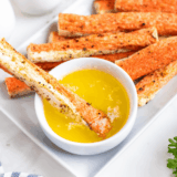 Golden crispy air fryer crab bites on a white plate with garlic butter dipping sauce