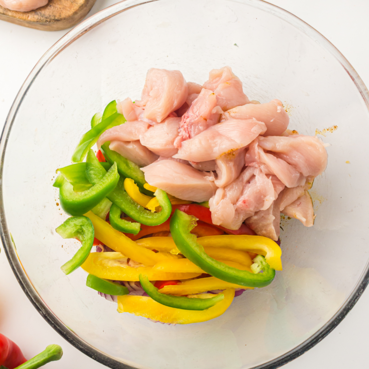Bell pepper and onion strips tossed with olive oil and fajita seasoning in a large bowl before air frying.