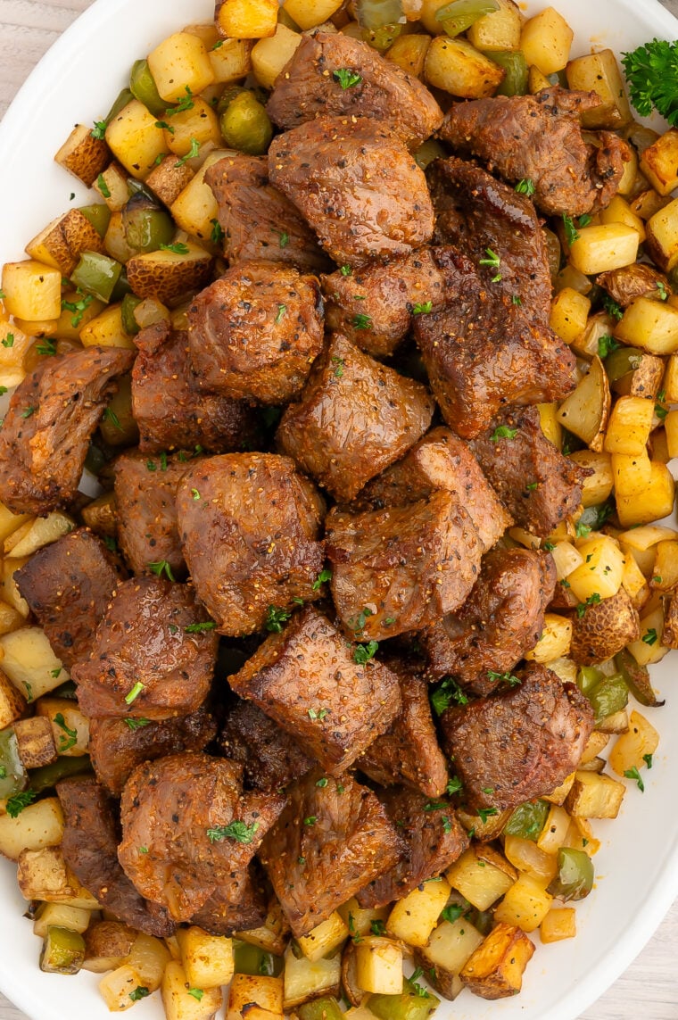 Garlic butter steak bites served over seasoned air fryer potatoes