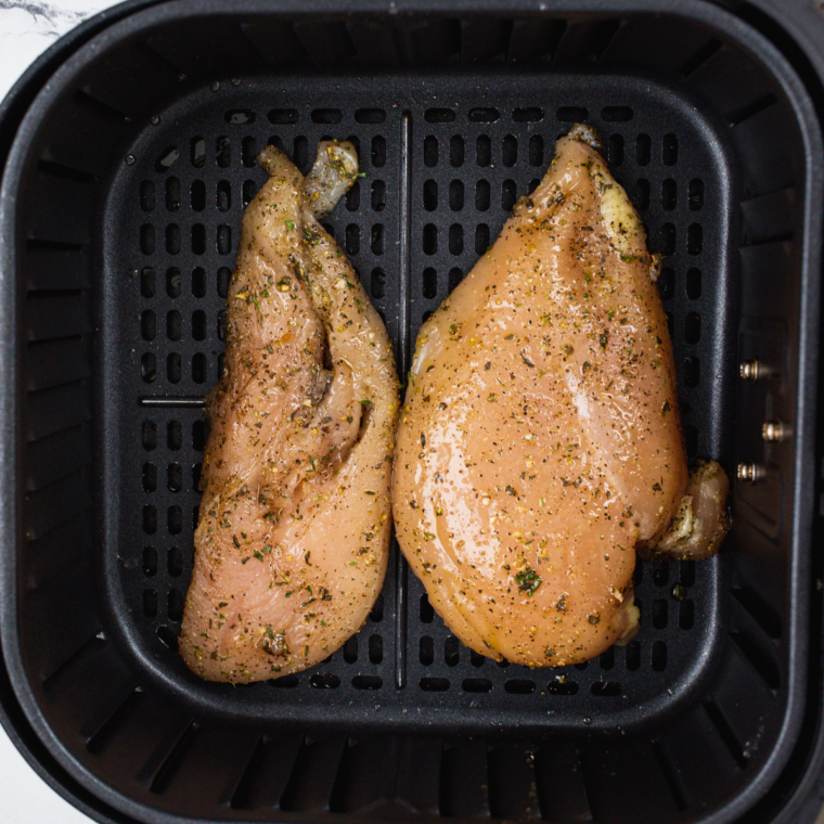 Prepare the Chicken: Seasoned chicken breasts cooking in a skillet or air fryer basket. until golden brown.