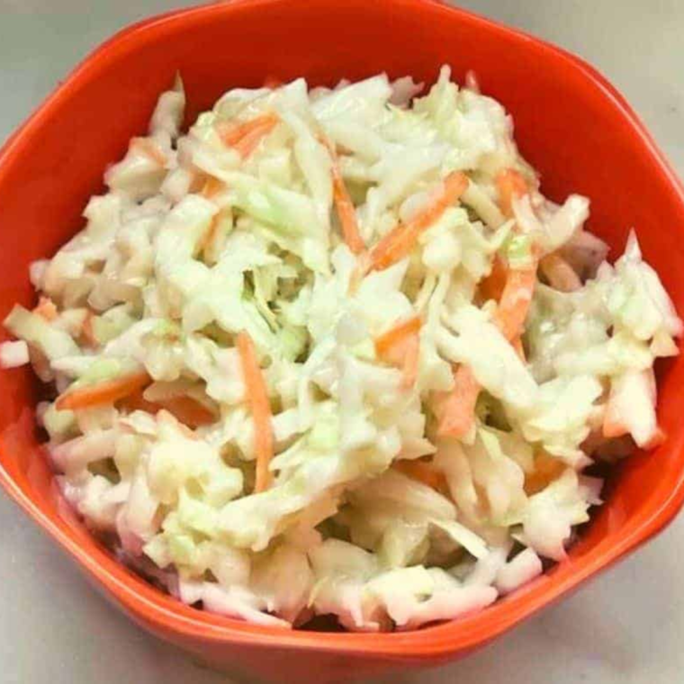 A bowl of creamy Copycat KFC Coleslaw, made with shredded cabbage and carrots, featuring a rich and tangy dressing, served as a side dish perfect for summer barbecues or fried chicken meals.