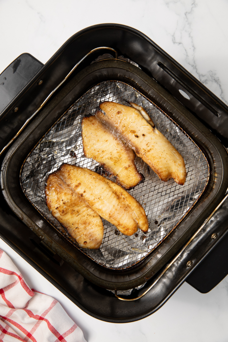 Golden air fryer walleye fillets served on a plate with fresh lemon wedges