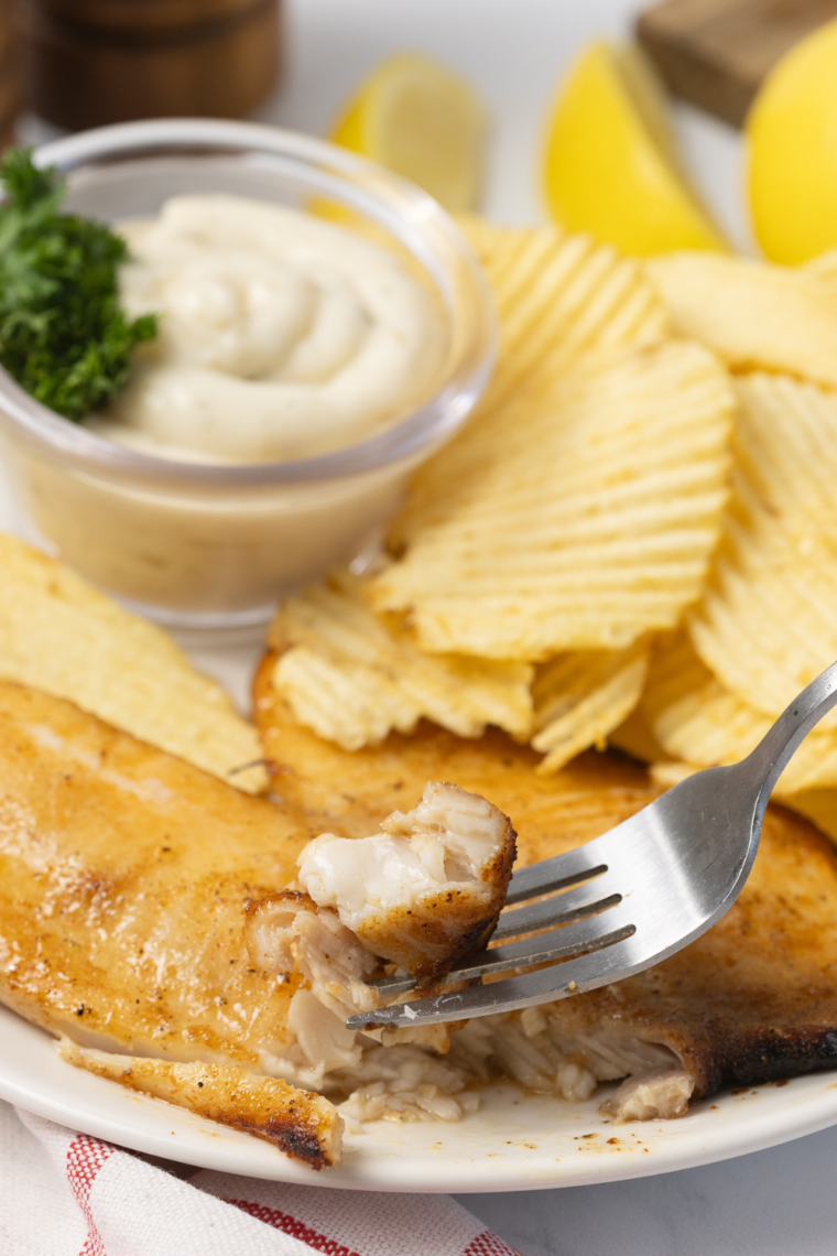 Air fryer walleye fillets with no breading served golden and flaky on a plate with lemon wedges and fresh herbs