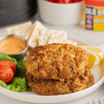 Frozen crab cakes cooking in air fryer basket, golden brown and crispy edges
