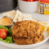 Frozen crab cakes cooking in air fryer basket, golden brown and crispy edges