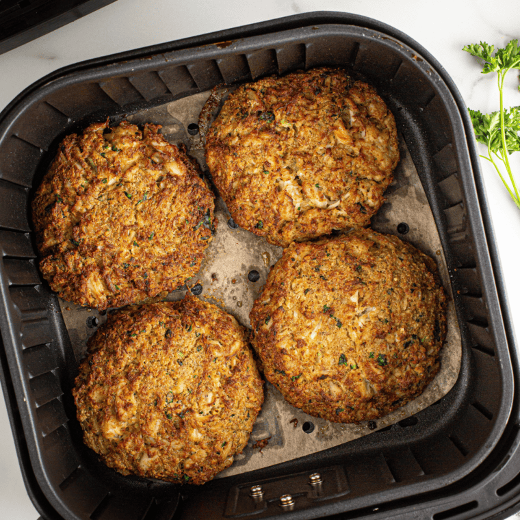 Frozen crab cakes arranged in a single layer inside air fryer basket for even cooking