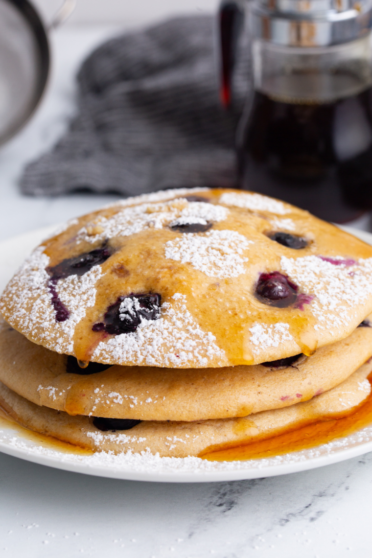 Warm fluffy pancakes reheated and served with syrup on breakfast plate