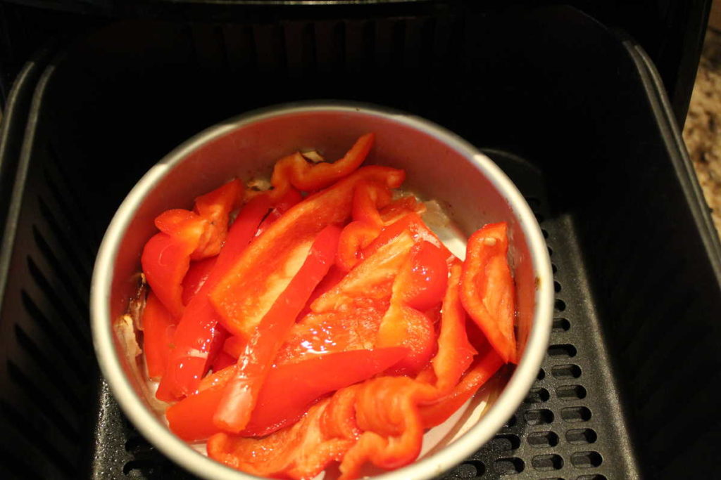 sliced red bell pepper in a metal pan in air fryer basket
