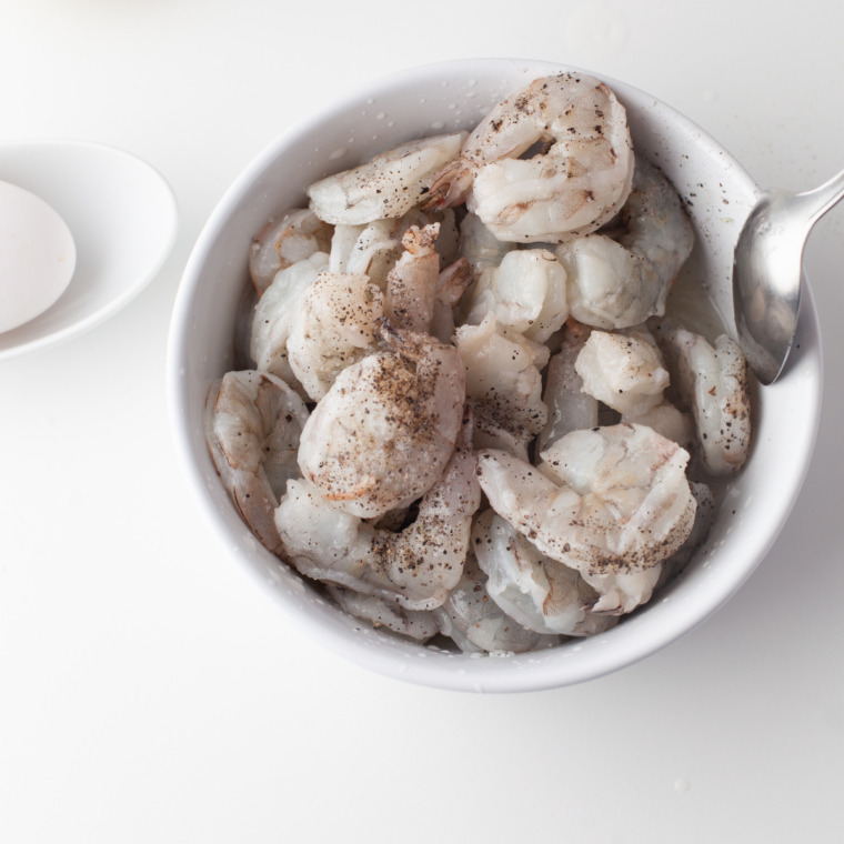 Raw shrimp peeled and deveined, sliced into butterfly shape on a cutting board, ready for coating.