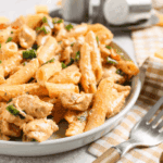 Top-down view of creamy Cajun chicken pasta topped with air-fried blackened chicken breast and fresh parsley.