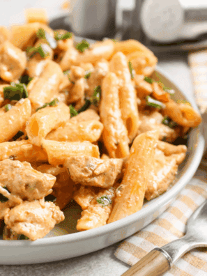 Top-down view of creamy Cajun chicken pasta topped with air-fried blackened chicken breast and fresh parsley.