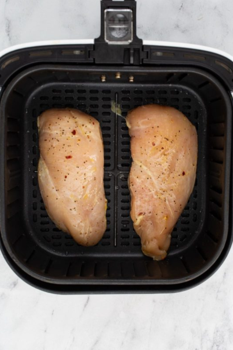 Placing chicken into the air fryer basket. 