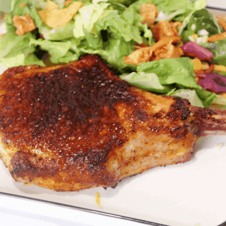 Juicy Air Fryer Chile Lime Pork Chop garnished with lime wedges and fresh herbs, ready to serve.