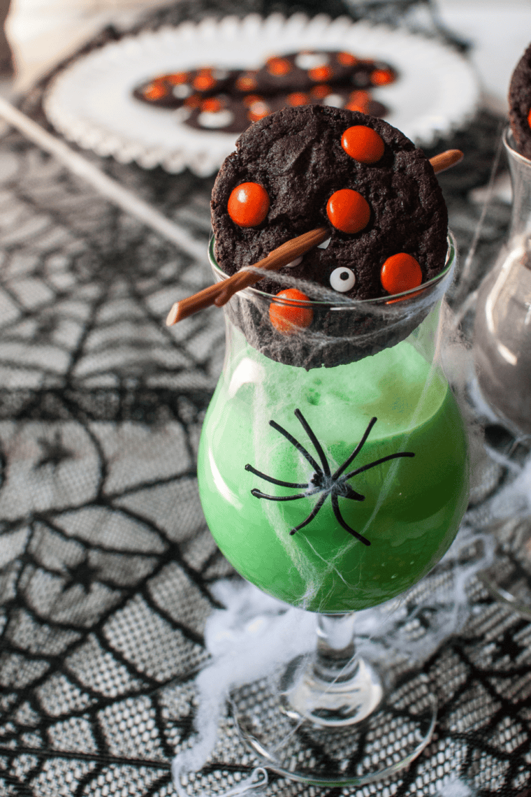 A batch of thick, dark chocolate cookies topped with vibrant orange M&M's and spooky white candy eyeballs, cooling on a wire rack to show their soft, fudgy texture.