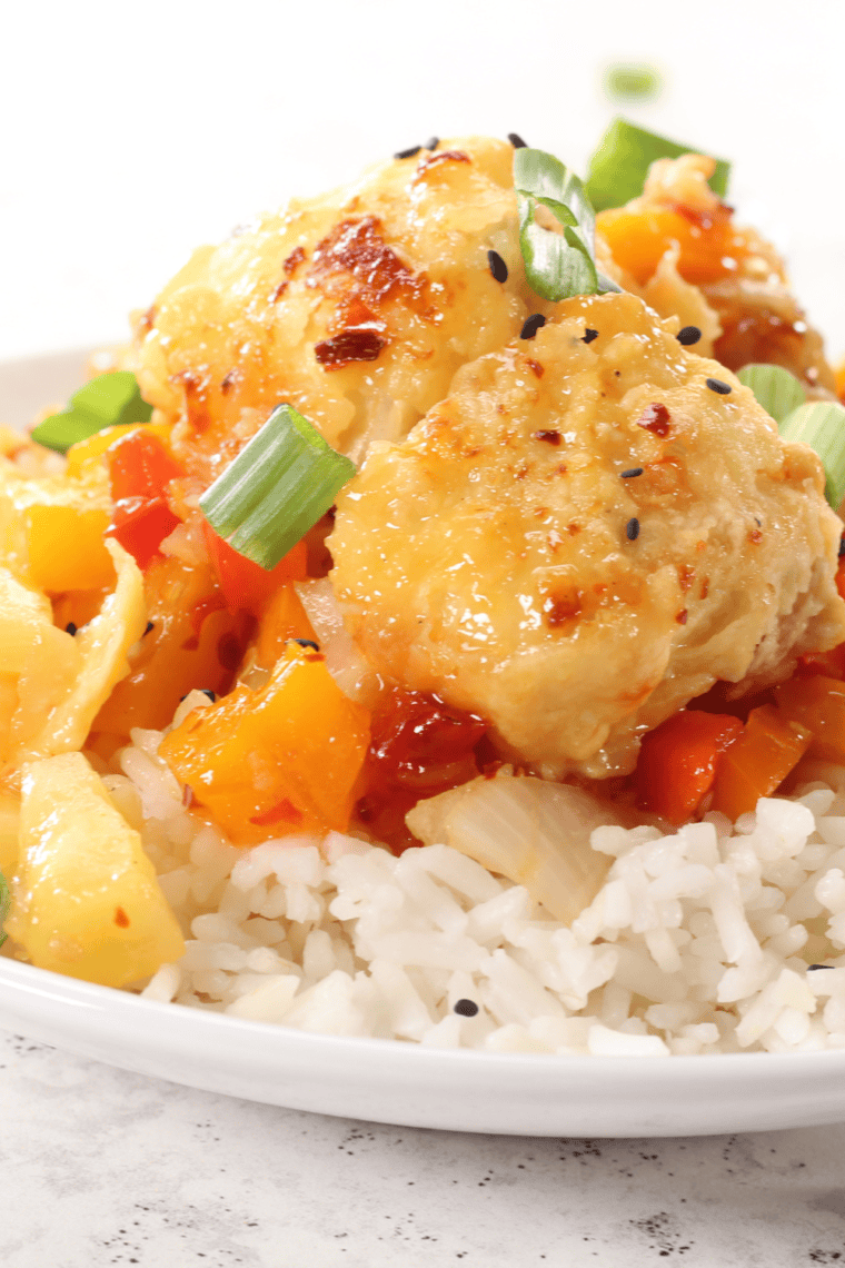 A plate of Air Fryer Panda Express Sweet Fire Chicken Copycat with crispy chicken, peppers, onions, and pineapple, drizzled with sweet chili sauce.