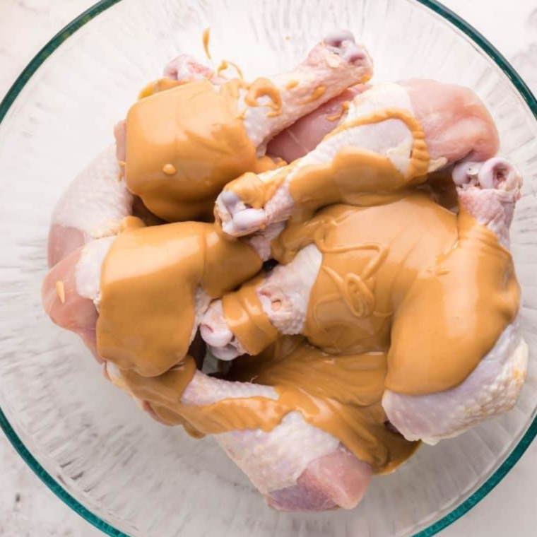 In a mixing bowl, combine peanut butter, coconut milk, honey, salt, soy sauce, grape jelly, jalapenos, red chili sauce, rice wine vinegar, garlic powder, and coarse black pepper to create the marinade.