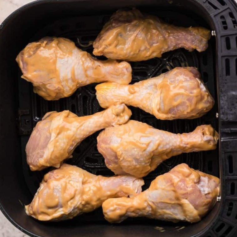 Place the marinated chicken drumsticks in the air fryer basket, ensuring they are spaced apart for even cooking.