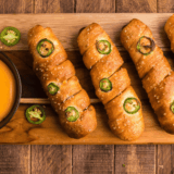Golden air fryer pretzel cheese dogs on a plate with queso dip