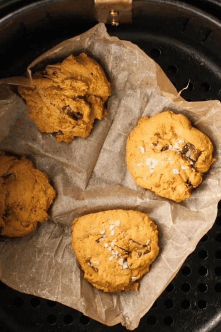 Air fryer with pumpkin cookies baking, edges turning golden brown.