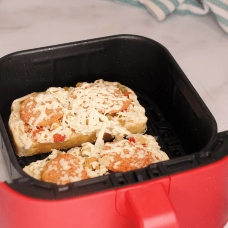 Frozen pizza melt split into two open-faced halves, separated to show topped bread ready for air fryer cooking.