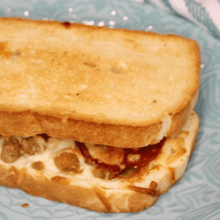 Air fryer Red Baron pizza melt sandwich cut in half with melted cheese and pepperoni