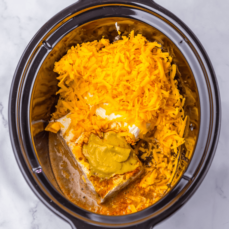 Ingredients for beer cheese dip laid out including shredded cheddar, cream cheese, butter, and beer