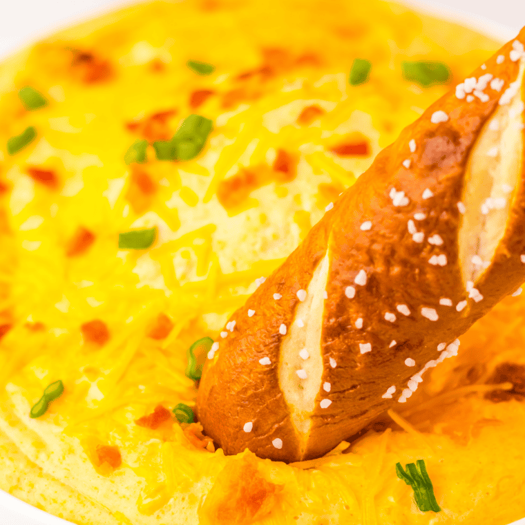 Serving warm beer cheese dip in a bowl with soft pretzels for dipping