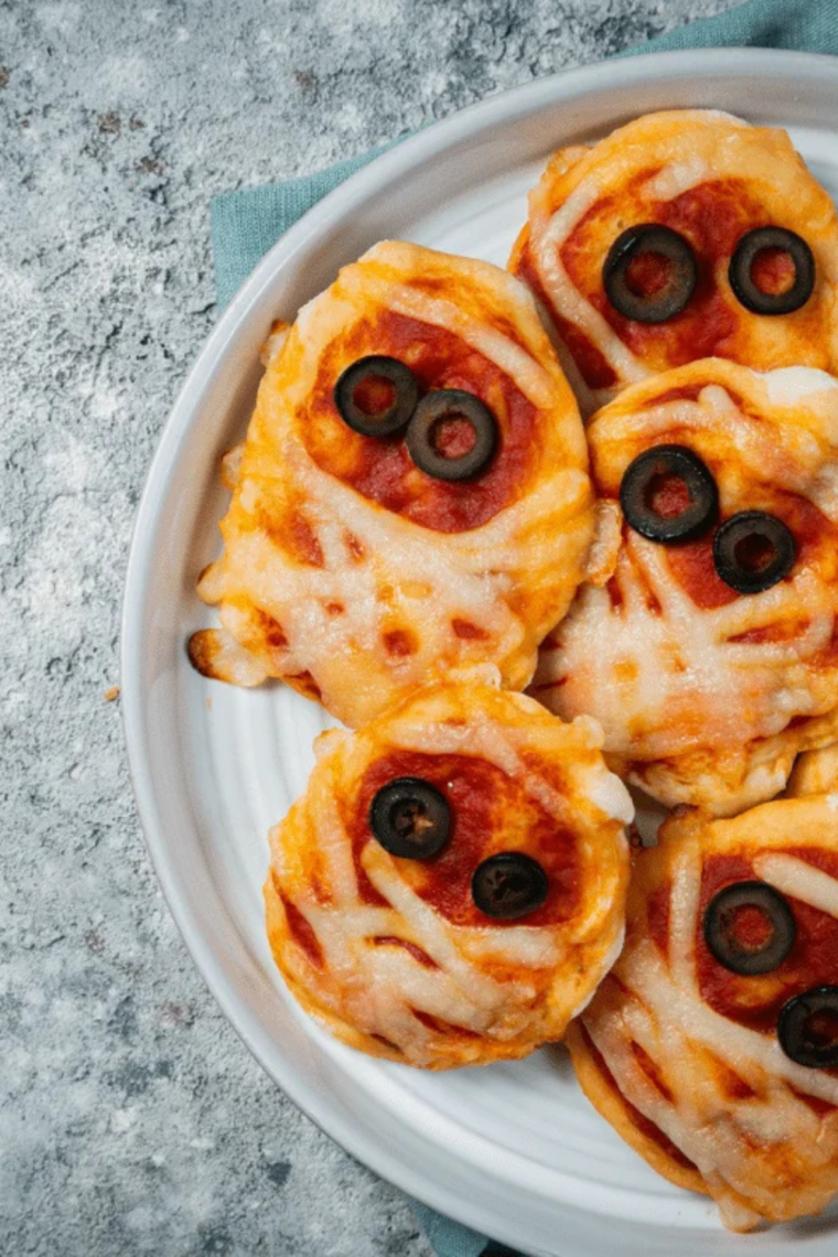 Halloween mummy pizza cooked in air fryer basket with golden crescent dough edges