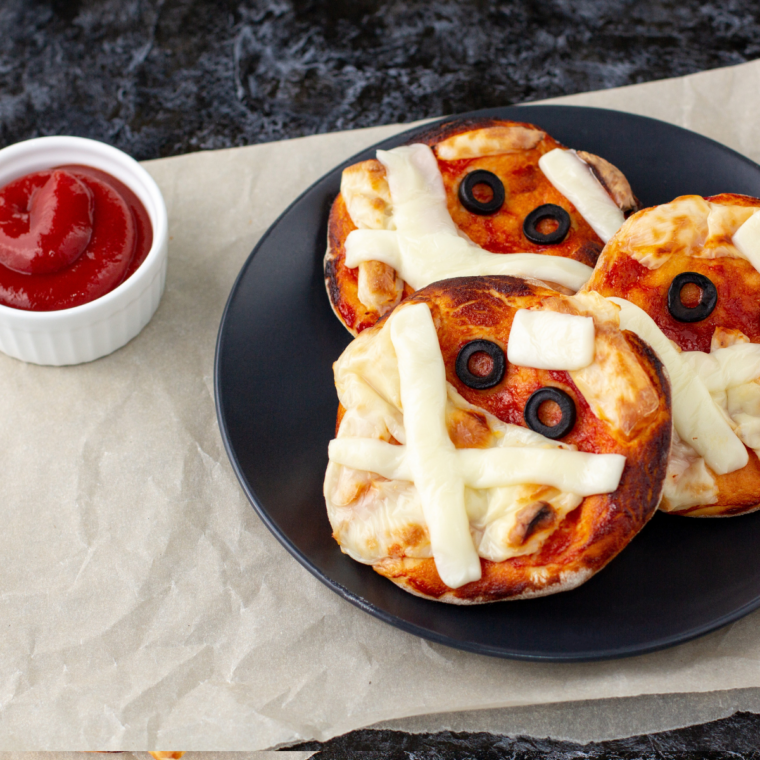Close-up of mummy-shaped air fryer pizza with olive eyes and melted mozzarella strips